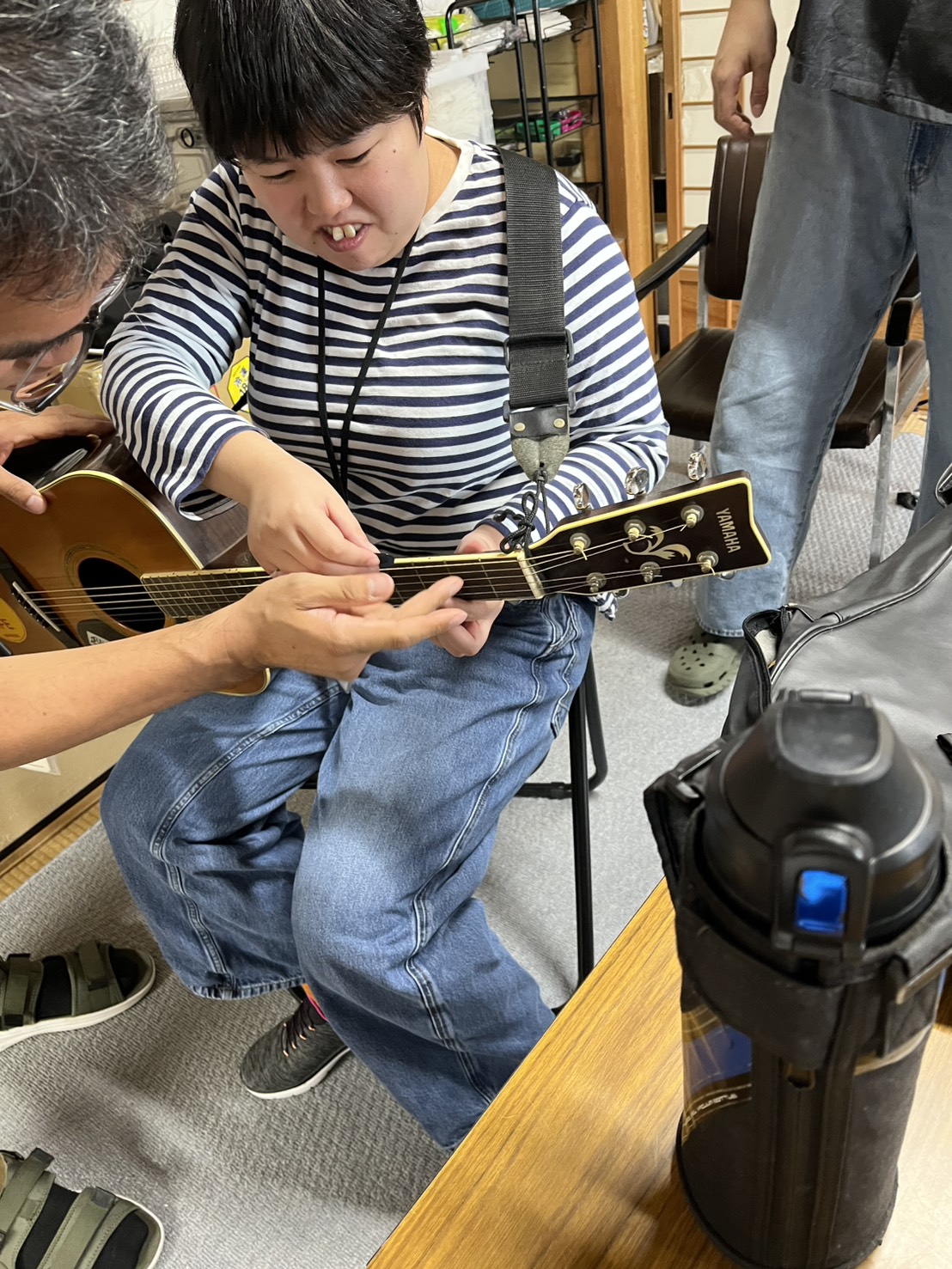 奈良県天理市の就労継続支援B型てんで、スタッフに教わりながらアコースティックギターに触れる利用者さん