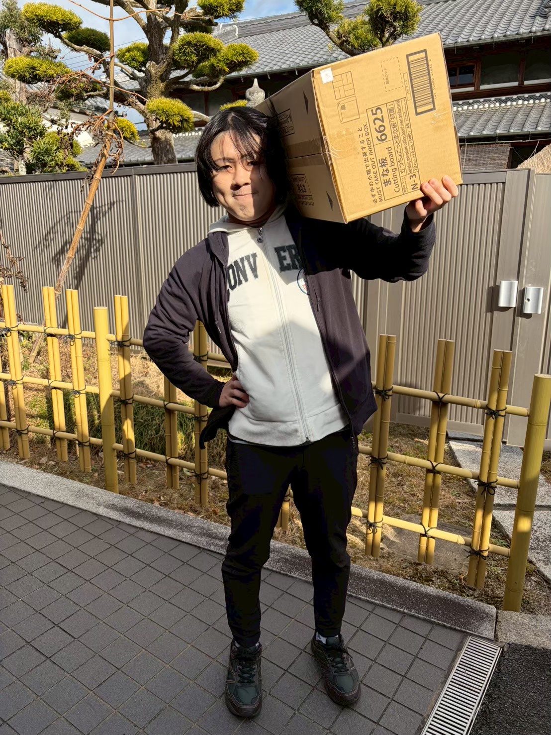 奈良県天理市の就労継続支援B型事業所てんで、段ボール箱を肩に担ぐ利用者の様子。明るい屋外での活動風景。